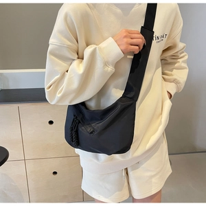 Detailed view of black nylon dumpling bag with adjustable shoulder strap on female model