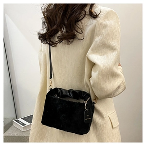 Close-up of black faux fur shoulder bag with ruched leather handle and gold hardware