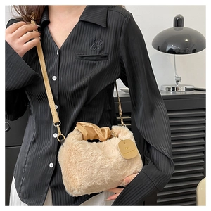 Detail of plush faux fur handbag with a metal chain strap and engraved slogan tag