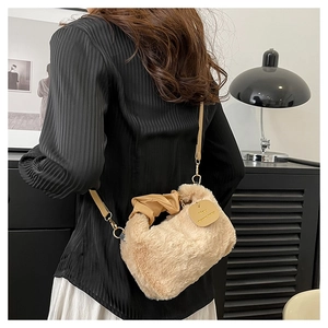 Detailed view of beige plush crossbody bag with leather strap and golden hardware accents