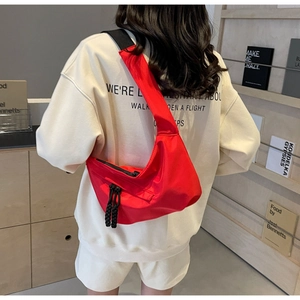 Detail of red nylon crescent crossbody bag with adjustable wide strap shown on model