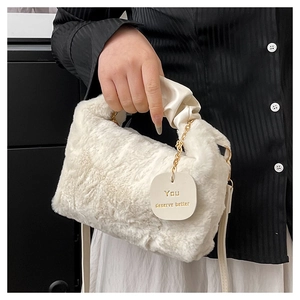 Close-up of white plush crossbody bag with ribbon handle and gold chain details