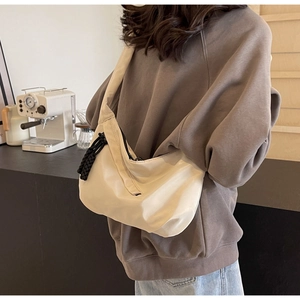 Off-white nylon hobo bag with black woven zipper detail worn by a model in casual style