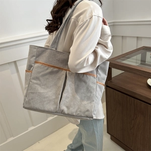 Chic light grey corduroy tote bag with brown piping shown on a model for daily commute