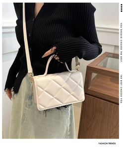 Détail du petit sac carré matelassé crème avec texture fine et garnitures dorées