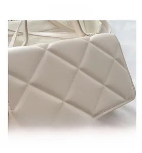 Détail du motif en losanges matelassés et des coutures sur le sac bandoulière beige