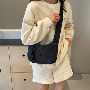 Minimalist black nylon crossbody dumpling bag with adjustable strap and woven zipper detail