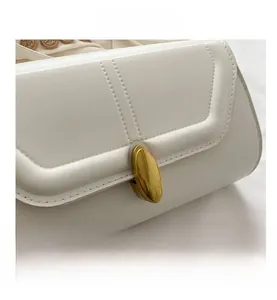 Détail macro du fermoir doré et des surpiqûres en U sur le sac à main en cuir blanc