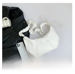 Détails d'un sac sous les bras blanc en forme de croissant avec bandoulière plissée