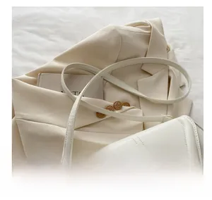 Détail d'un sac à bandoulière en cuir beige avec fermoir doré et sangle réglable