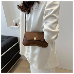 Detailed side view of the vintage brown leather shoulder bag with gold buckle on a model