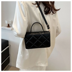 Détail du sac bandoulière matelassé noir montrant la bandoulière et les boucles dorées