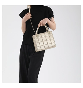 Detailed view of champagne gold quilted crossbody bag with metallic chain and round handles