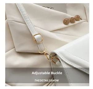 Détail de la boucle dorée réglable et de la bandoulière en cuir mat du sac blanc