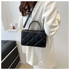 Gros plan d'un sac bandoulière noir matelassé avec motif losange et détails métalliques