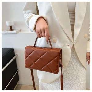 Détail du sac à bandoulière marron matelassé avec fermoir doré et texture en losange