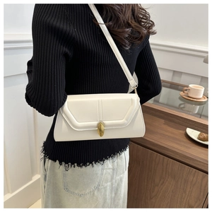 Détail du sac baguette crème avec fermoir ovale doré et coutures de précision