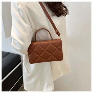 Détail du petit sac carré matelassé marron avec poignée et bandoulière sur mannequin