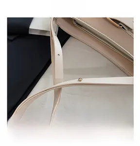 Detail view of the adjustable shoulder strap and gold metal buckle on a beige leather bag