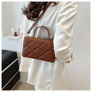 Détail d'un sac bandoulière matelassé marron foncé en cuir PU avec ferrures dorées
