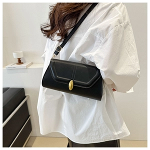 Détail du sac baguette noir avec bandoulière réglable et fermoir en métal doré