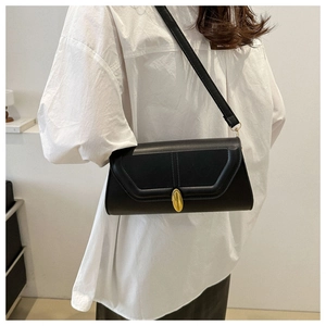 Gros plan d'un sac baguette noir minimaliste avec une boucle dorée sur un mannequin
