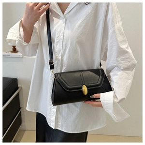 Détail du sac baguette en cuir noir minimaliste avec un fermoir ovale doré poli élégant