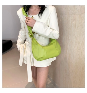 Détail de bandoulière plissée sur un sac hobo vert lime porté avec un blazer blanc