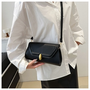 Détail d'un sac bandoulière chic en cuir noir doté d'un fermoir en métal doré classique