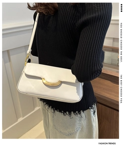 Detail of white minimalist faux leather shoulder bag with golden half-moon metal buckle