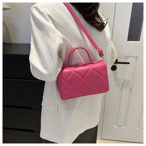 Gros plan du sac matelassé rose fuchsia avec poignée et détails en métal doré
