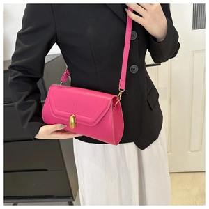 Détail d'un sac baguette rose vif montrant le fermoir rotatif doré et les coutures fines