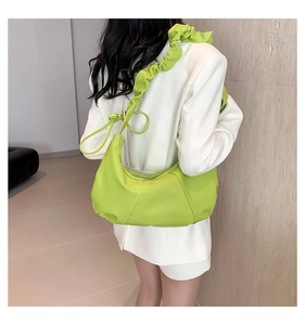 Détail latéral du sac à bandoulière plissé vert vif porté avec un blazer blanc élégant