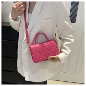 Détail d'un sac bandoulière rose matelassé sur mannequin en blazer blanc chic