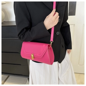 Détail du sac à bandoulière rose fuchsia avec fermoir doré ovale sur un mannequin