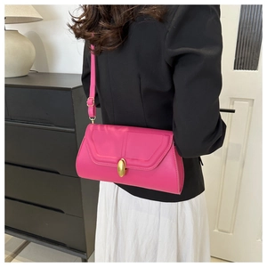 Sac bandoulière magenta chic avec gaufrage en V et boucle dorée porté par un mannequin