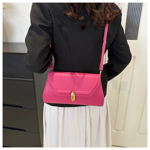 Détail du sac baguette fuchsia avec boucle dorée élégante et bandoulière fine