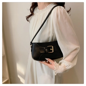 Detail of a vintage black leather crossbody bag with a large gold square buckle on the strap