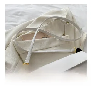 Detail showing white leather shoulder bag with gold clasp and adjustable strap