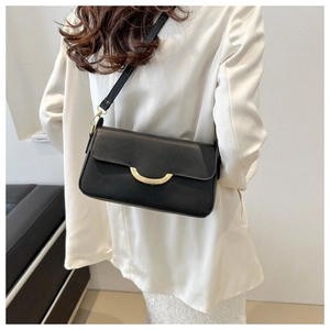 Detail of black matte leather shoulder bag with gold-tone curved metal buckle and strap