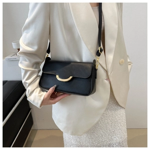 Close-up of minimalist black leather crossbody bag with elegant gold crescent metal buckle