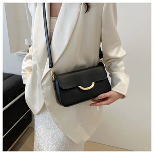 Minimalist black leather crossbody bag with elegant gold arc buckle worn by model
