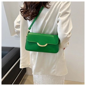 Detail of a bright green leather handbag with a gold semi-circular buckle on white blazer