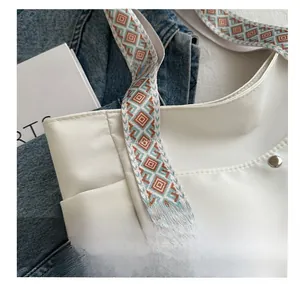 Detail of white tote bag with colorful ethnic geometric woven strap and metal snap