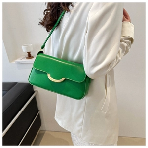Close-up of bright green leather shoulder bag with gold moon buckle on a model