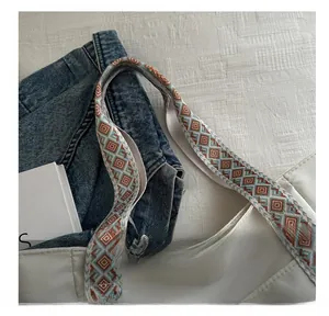 Detail of white tote bag featuring colorful geometric woven strap and smooth stitching
