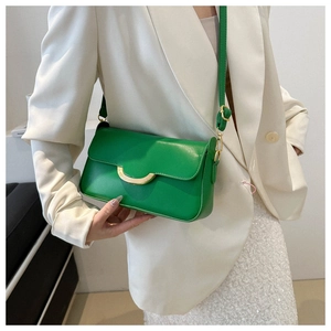 Detail of bright green square handbag with gold crescent buckle and adjustable strap