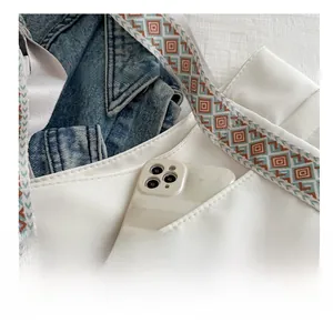 Detail of white tote bag featuring front storage pocket and bohemian jacquard strap