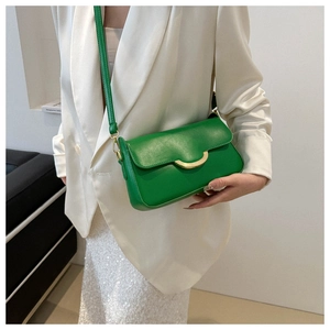 Detail shot of the green faux leather handbag featuring a golden half-moon metal buckle