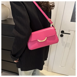 Detail of fuchsia shoulder bag with gold crescent hardware on black blazer outfit
